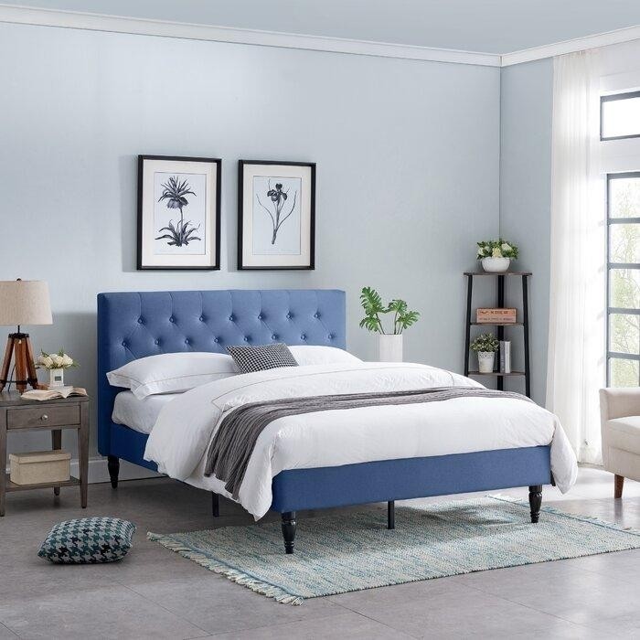 светло-голубая спальня с синей мягкой кроватью и серо-коричневой прикроватной тумбочкой с трехногой настольной лампой.jpeg